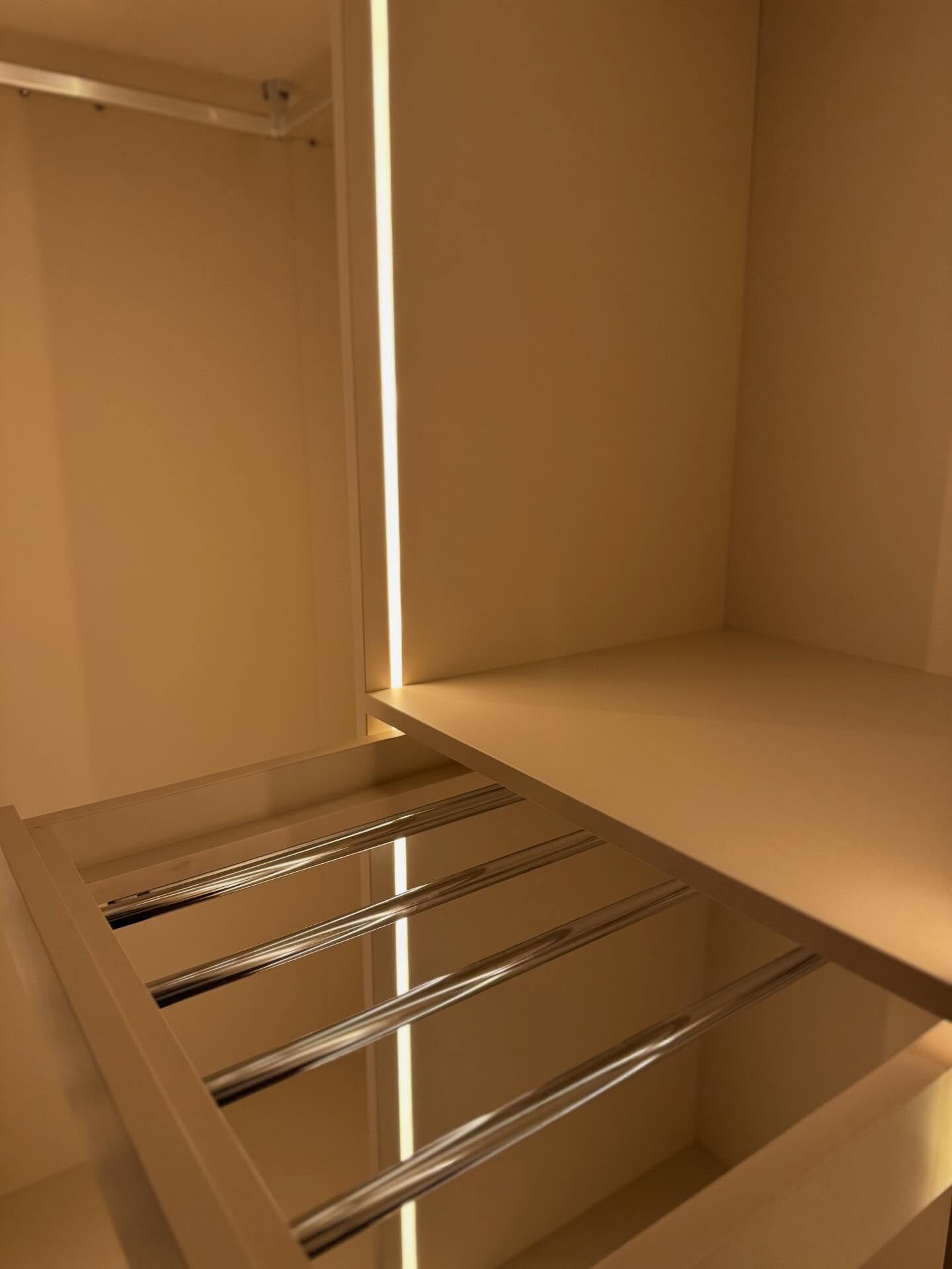 Pormenor do interior de um armário com varão extraível e iluminação